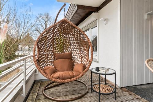 a wicker chair sitting on a porch at Ahorn - Balkon, Garage, BBQ, Switch&Beamer, Flexbetten, Zentral, 15min in Willingen in Brilon