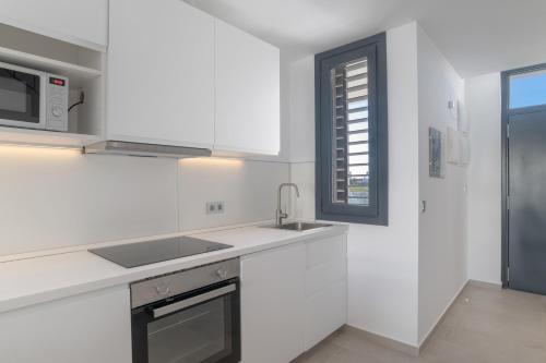 a white kitchen with a sink and a microwave at Palacio de pilas 22 in Zahara de los Atunes