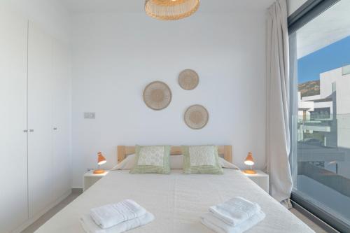 a white bedroom with a large bed with two towels at Palacio de pilas 22 in Zahara de los Atunes