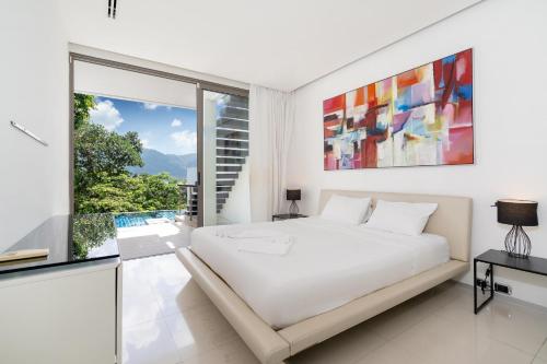 a bedroom with a white bed and a large window at Atika Villa 7 ocean view pool villa in Patong Beach
