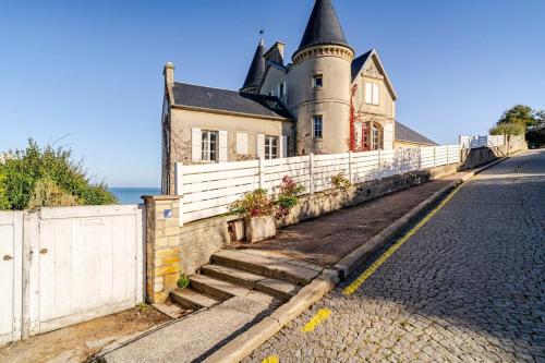 une vieille maison avec une clôture blanche à côté d'une rue dans l'établissement Maison Historique Vue mer exceptionnelle, à Arromanches-les-Bains