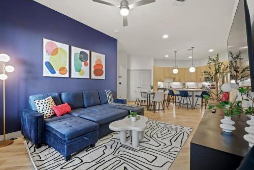 a living room with a blue couch and a kitchen at Stylish 2BR Apartment, Near Galleria Dallas, Free Parking, Gym & Pool in Dallas