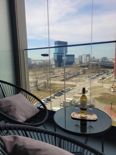 a glass table with a bottle of wine sitting on a balcony at Apartament OneStreet in Katowice
