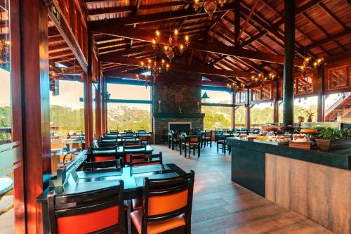 a restaurant with tables and chairs and a fireplace at Pousada Recanto dos Sonhos in Campos do Jordão