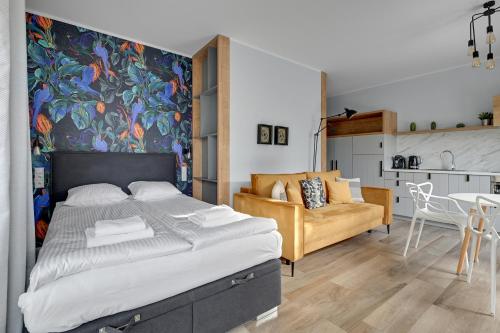 a bedroom with a large bed and a kitchen at Bursztynowa - Apartamenty przy Plaży in Gdańsk