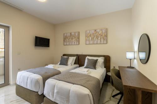 a bedroom with two beds and a desk and a mirror at Elysian Villas - With 2 Private Pools in Roumelí