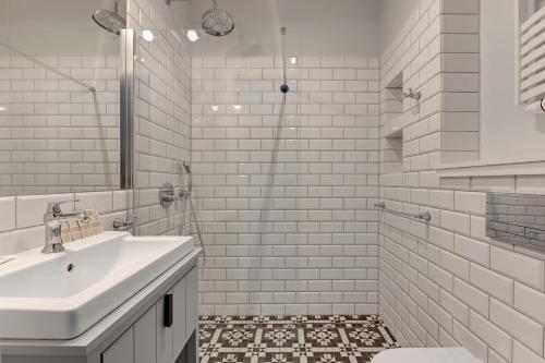 a white bathroom with a sink and a shower at Bursztynowa - Apartamenty przy Plaży in Gdańsk