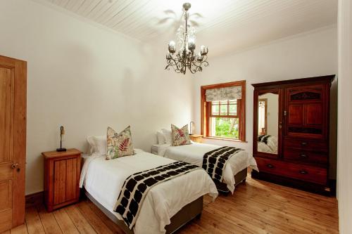 a bedroom with two beds and a chandelier at Double Story at 55 in Graaff-Reinet