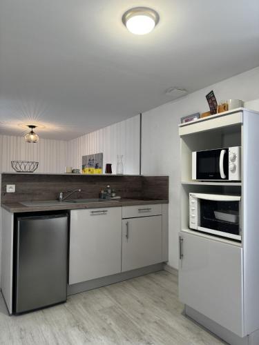 une cuisine avec des armoires blanches et des appareils en acier inoxydable dans l'établissement le Cozy Bayeusain, à Bayeux