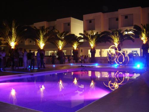 a swimming pool lit up at night with lights at L'eros Hotel in Ayia Napa