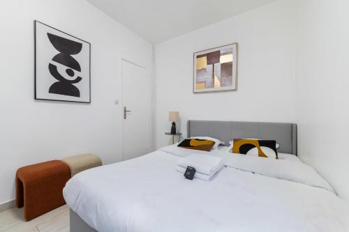 - une chambre blanche dotée d'un grand lit avec des oreillers jaunes et noirs dans l'établissement Appartement cosy hopital bichat - paris 18 - 4P, à Paris