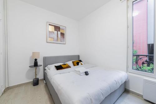 une chambre blanche avec un lit et une fenêtre dans l'établissement Appartement cosy hopital bichat - paris 18 - 4P, à Paris