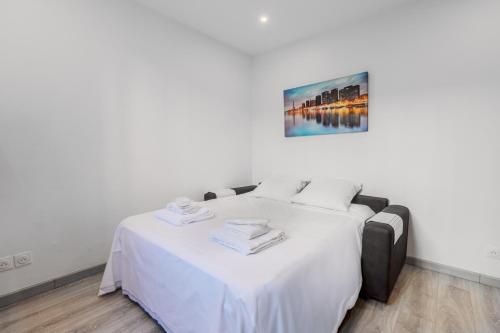 - une chambre dotée d'un lit avec des draps blancs et un tableau dans l'établissement Orteaux - Cosy studio proche Père Lachaise, à Paris