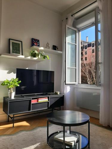a living room with a tv and a table and a window at Haussmannien rénové et climatisé, Centre de Lyon in Lyon