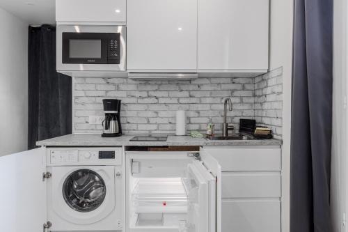 une cuisine avec un lave-linge et un micro-ondes dans l'établissement Orteaux - Cosy studio proche Père Lachaise, à Paris
