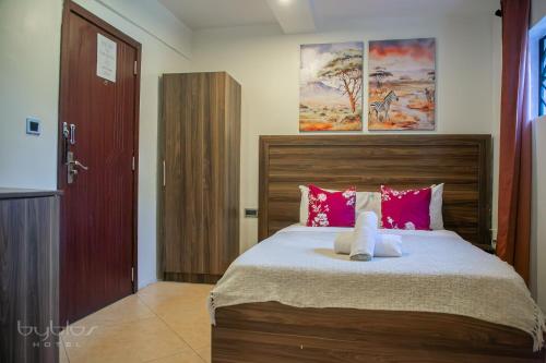 a bedroom with a large bed with pink pillows at Byblos Hotel-Sky Osu in Accra