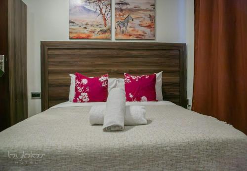 a bedroom with a bed with pink and white pillows at Byblos Hotel-Sky Osu in Accra