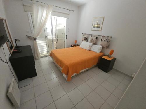 a bedroom with a bed with an orange bedspread at Hadar's in Yeroskipou
