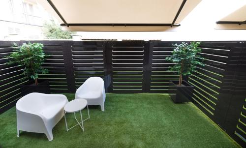 a garden with two white chairs and green grass at TURINHOMETOWN Residence Apartments in Turin