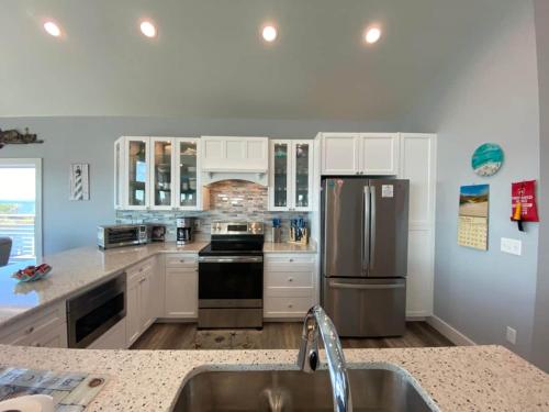 a kitchen with white cabinets and a stainless steel refrigerator at Kokomo Sands in Hatteras