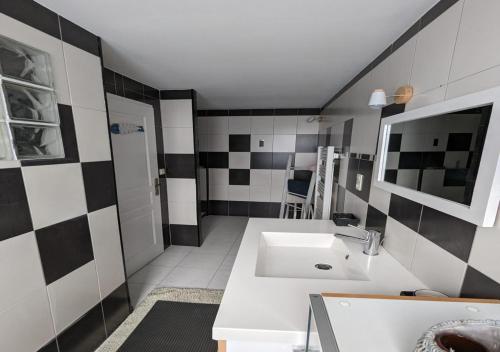 La salle de bains est pourvue d'un lavabo blanc et de carrelage noir et blanc. dans l'établissement GITE PAMPHILIENNE VUE MONT SAINT MICHEL et CAMPAGNE NORMANDE, à Courtils