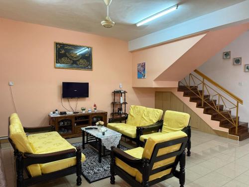 a living room with yellow furniture and a staircase at B'Mar Homestay in Tawau