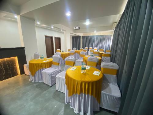 a room with tables and chairs with yellow table cloths at Hotel StayBird - Nest, Kharadi in Pune