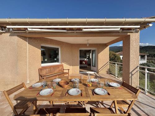 - une table en bois avec des assiettes et des verres sur la terrasse dans l'établissement Villa 