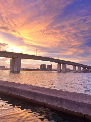 a bridge over a body of water with a sunset at Naha Airport, beaches, shopping centers are nearby #NewVilla in Itoman