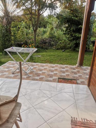 a table and a chair on a patio at Les Gîtes du Sud - Ô Naturel in Gourbeyre