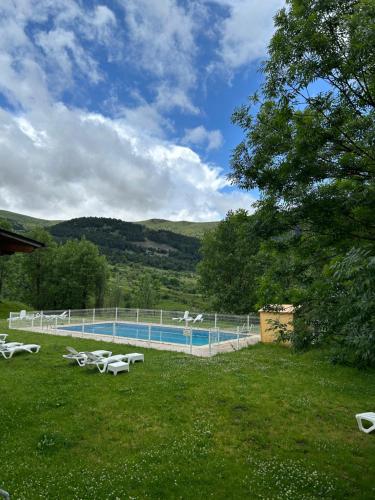 a swimming pool with tables and chairs in a field at Hotel Taüll in Pla de l'Ermita