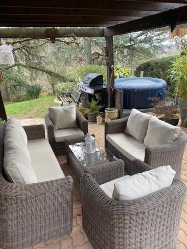 a patio with wicker chairs and couches and a grill at Chambre avec terrasse in LʼIsle-Jourdain