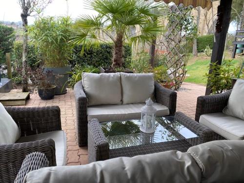 a patio with wicker furniture and a table with a bottle on it at Chambre avec terrasse in LʼIsle-Jourdain