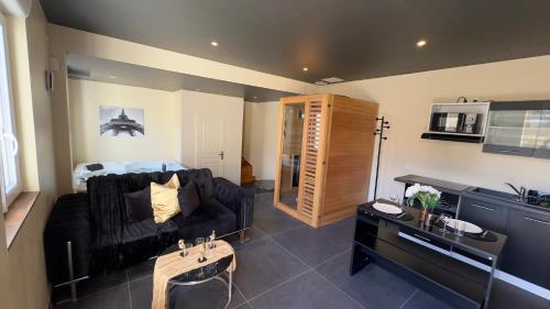 un salon avec un canapé noir et une cuisine dans l'établissement Magnifique loveroom avec sauna, spa et cinémaroom, à Fontenoy