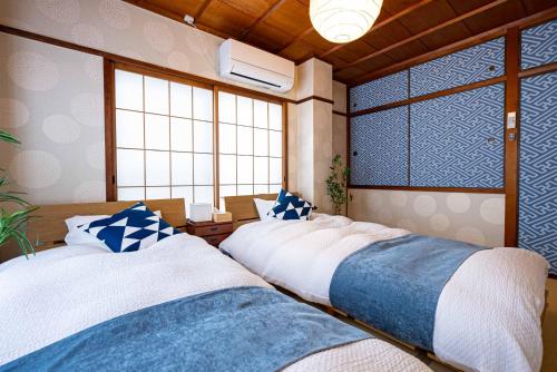 two beds in a room with windows at MOMOYA tsudoi 和風 岡山清輝橋駅徒歩1分 貸切 駐車場付 in Okayama