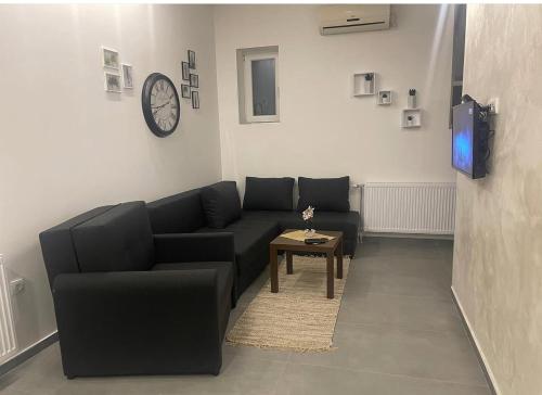 a living room with a black couch and a table at TEPIĆ Garni Hotel in Temerin