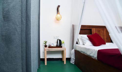 a bedroom with a bed with red pillows and a table at Mountain Breeze Villa in Ella
