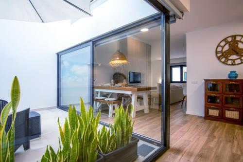 a living room with sliding glass doors and plants at PÉ NA AREIA II by Stay in Alentejo in Vila Nova de Milfontes