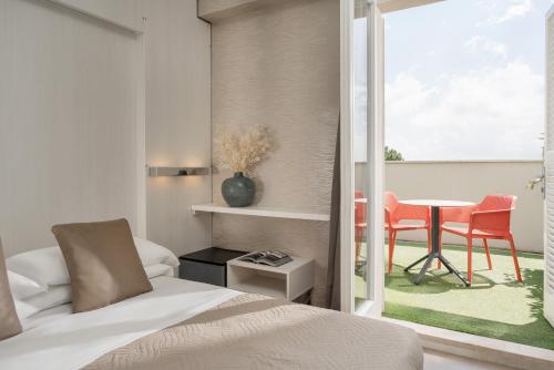 a bedroom with a bed and a table with chairs at Hotel San Marco in Milano Marittima