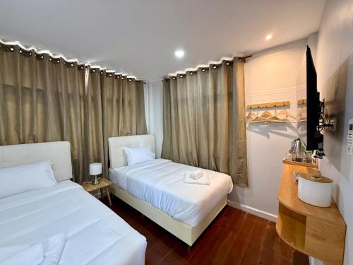a hotel room with two beds and a window at Brown House Cha am in Cha Am