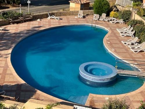 une grande piscine bleue avec des chaises longues. dans l'établissement Ajaccio appartement vue mer, à Ajaccio