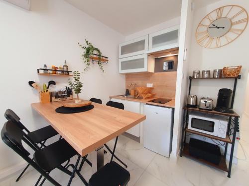 une cuisine avec une table en bois et quelques chaises dans l'établissement T2 Magellan Centre-ville - Clim Wifi Terrasse - ROSSIconciergerie - Linge inclus, à La Grande Motte