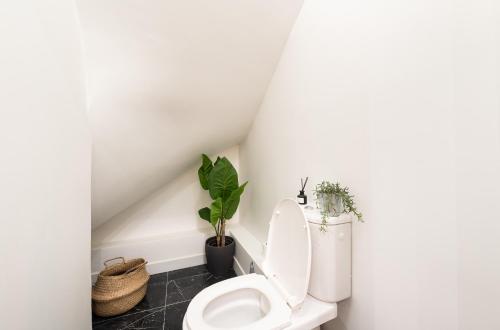 La salle de bains est pourvue de toilettes blanches et de plantes. dans l'établissement Le Marais l 5BR & AC - Duplex Home in Paris, à Paris