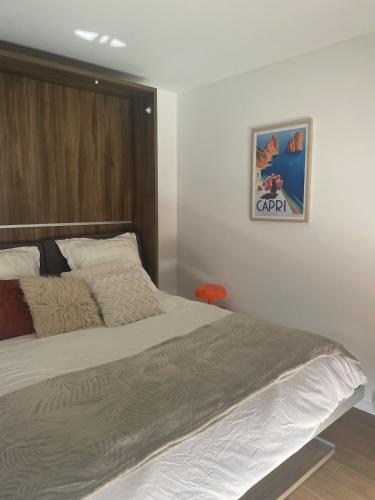 une chambre avec un grand lit avec un tableau sur le mur dans l'établissement Le Riviera - Studio Neuf & Lumineux - Avec Balcon, à Vincennes