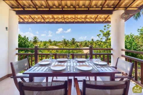 a table on a balcony with a view of the ocean at Reserva Imbassaí - Apartamento TD 11 02 Superior - Buganvílias in Imbassai