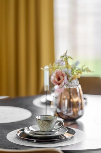 a table with a cup of coffee and a vase of flowers at Sauna Moments Villa in Torhout