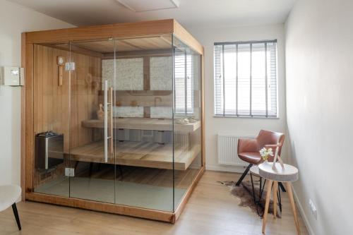 a glass cabinet in a room with a table and a chair at Sauna Moments Villa in Torhout