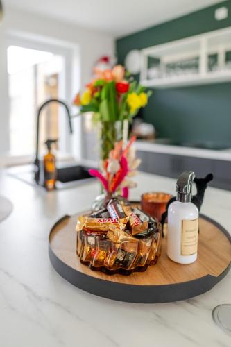 a wooden tray with a bottle of soap and flowers on a kitchen counter at Sauna Moments Villa in Torhout