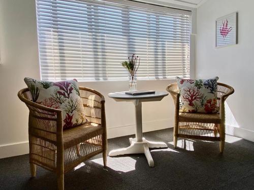 two chairs and a table in a room with a window at Hermanus Waterfront Apartment in Hermanus
