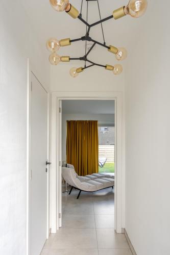 a chandelier hangs over a hallway with a couch at Sauna Moments Villa in Torhout